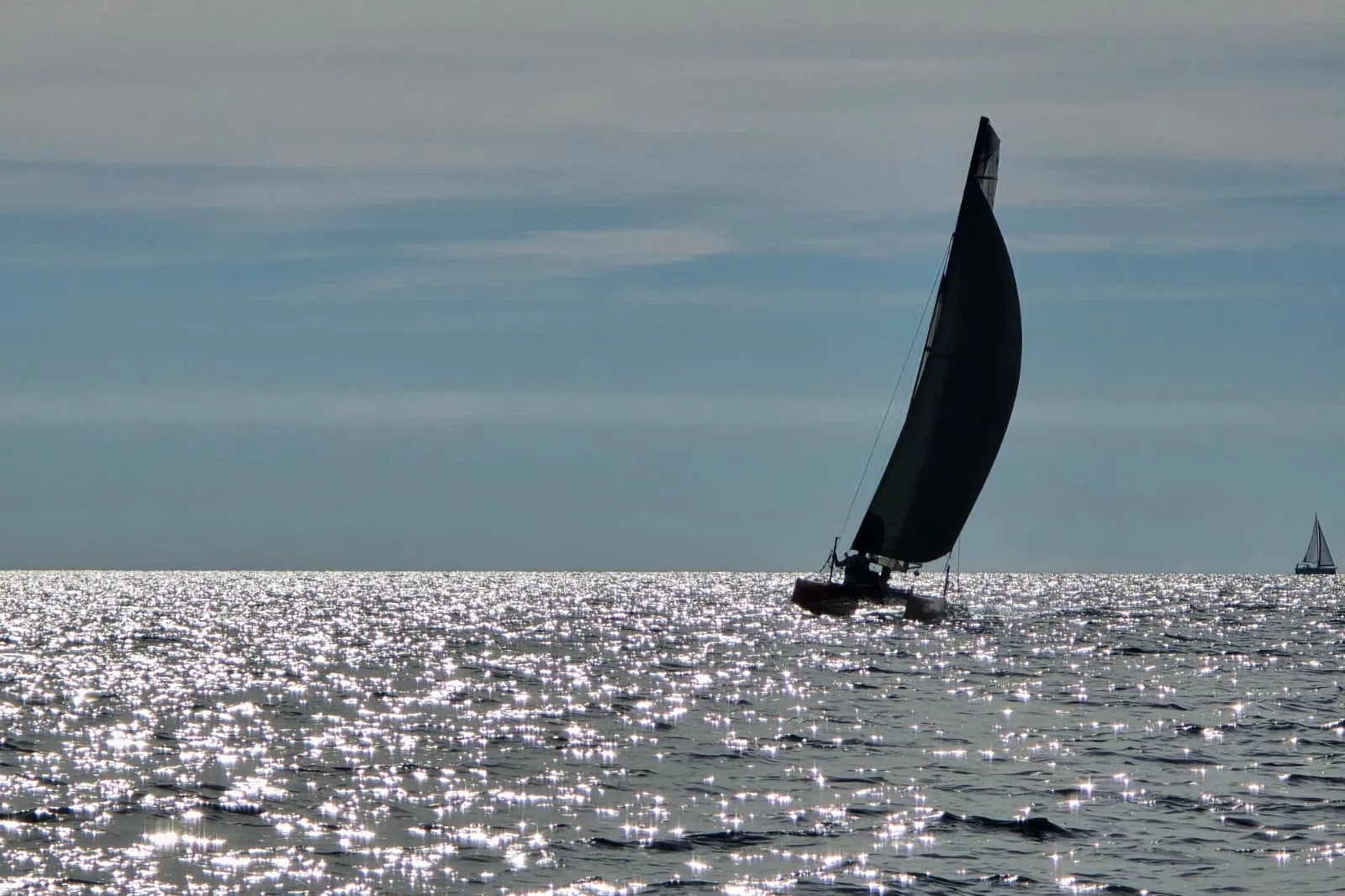 Silueta Hobie Wild Cata pod jedrima na svjetlucavom Jadranu pri zalasku sunca.